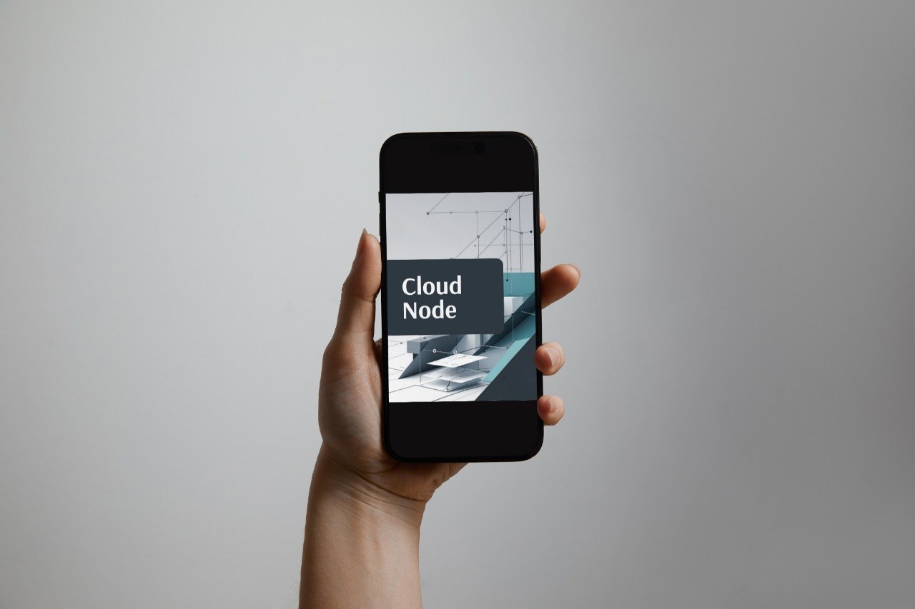 A hand holds a black smartphone against a light gray background. The phone screen displays the Cloud Node logo and interface.